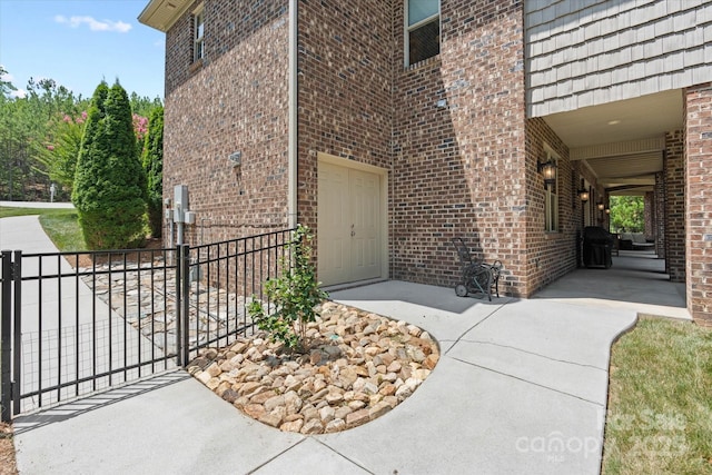 entrance to property with brick siding, fence, and a gate