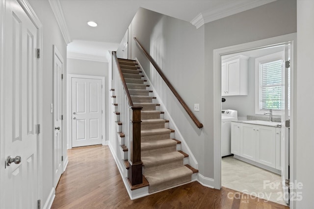 stairs with washer / clothes dryer, crown molding, and wood finished floors