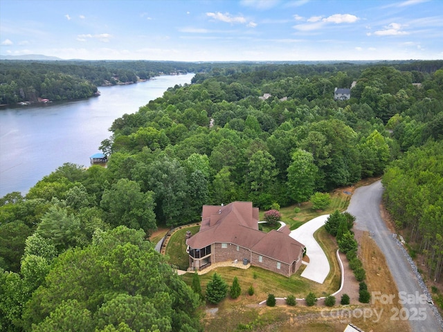 birds eye view of property featuring a forest view and a water view