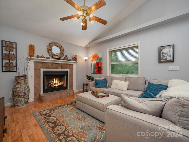 living room featuring ceiling fan, wood-type flooring, lofted ceiling, and a tiled fireplace