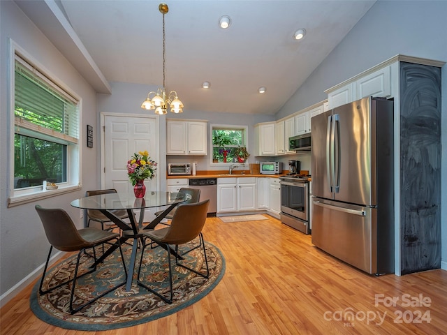 kitchen with hanging light fixtures, white cabinets, a healthy amount of sunlight, and stainless steel appliances