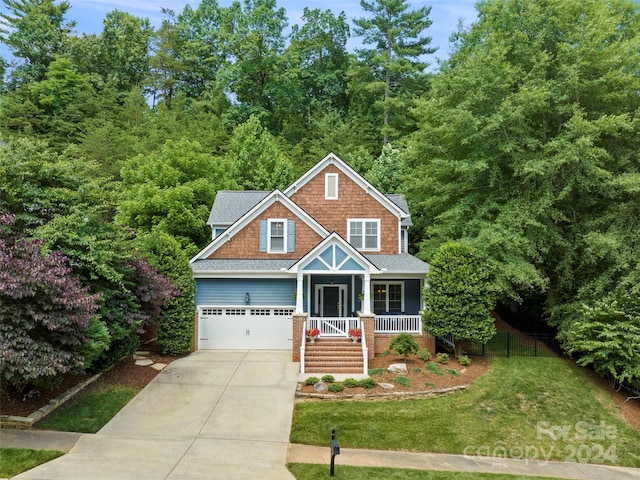 craftsman-style home featuring a garage, covered porch, and a front yard