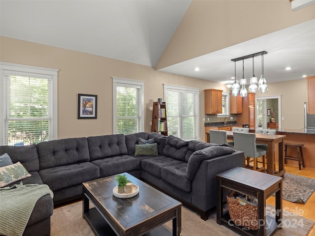 living room with sink, lofted ceiling, and light hardwood / wood-style flooring