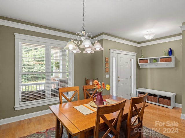 dining area featuring wood-type flooring, a notable chandelier, and ornamental molding