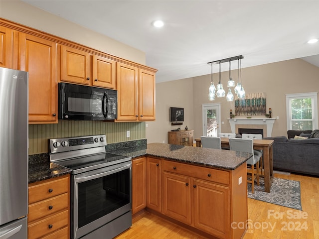 kitchen featuring decorative light fixtures, light hardwood / wood-style floors, kitchen peninsula, and stainless steel appliances