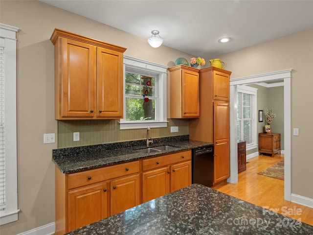 kitchen featuring plenty of natural light, sink, black dishwasher, and dark stone counters