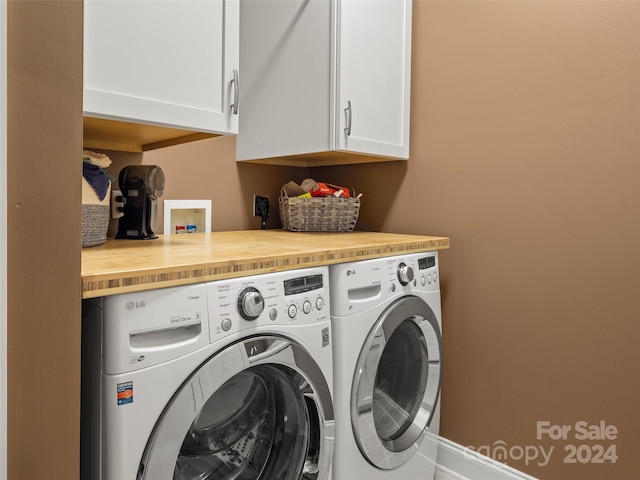 clothes washing area with separate washer and dryer and cabinets