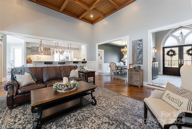 living room with dark hardwood / wood-style floors, beam ceiling, a towering ceiling, coffered ceiling, and wooden ceiling