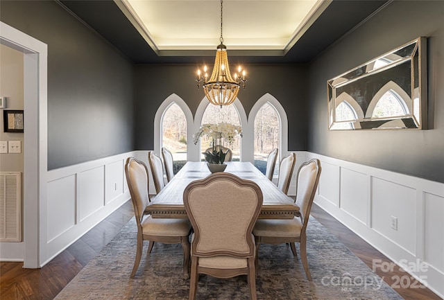 dining room with dark wood-type flooring, a tray ceiling, and a notable chandelier