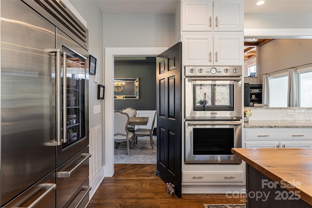 kitchen featuring white cabinets, butcher block countertops, appliances with stainless steel finishes, and dark wood-type flooring