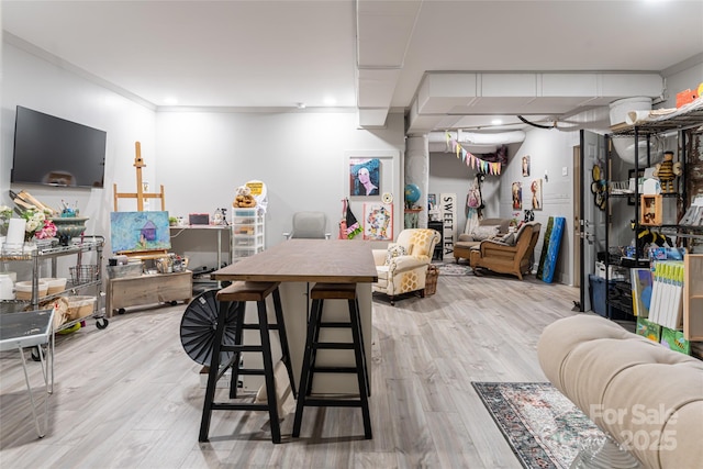 interior space featuring a breakfast bar, crown molding, and light hardwood / wood-style floors