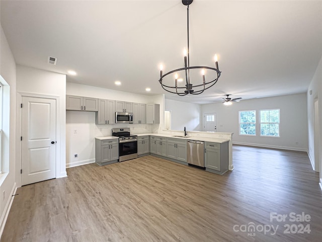 kitchen featuring stainless steel appliances, gray cabinetry, decorative light fixtures, light wood-type flooring, and sink