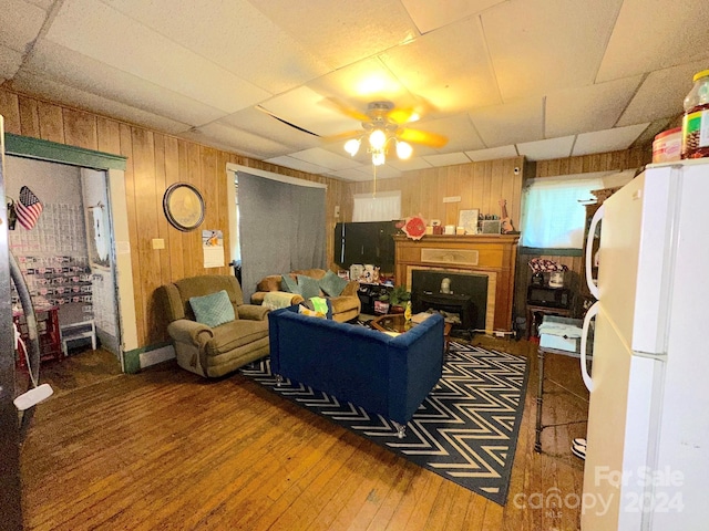 living room featuring ceiling fan, a paneled ceiling, and dark wood-type flooring