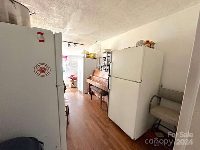 kitchen featuring wood-type flooring, a textured ceiling, white fridge, and rail lighting