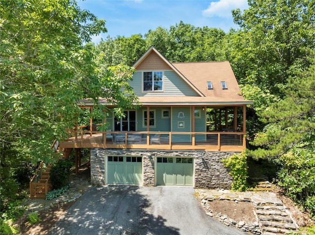 view of front of home with a garage, stone siding, and driveway