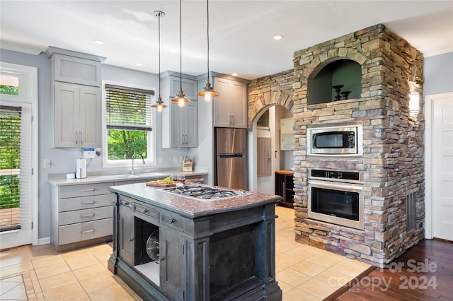 kitchen featuring hanging light fixtures, appliances with stainless steel finishes, gray cabinets, and a center island