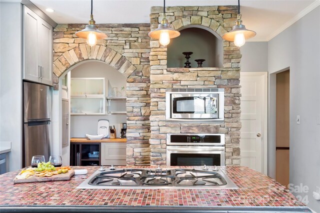 kitchen with appliances with stainless steel finishes, crown molding, and decorative light fixtures