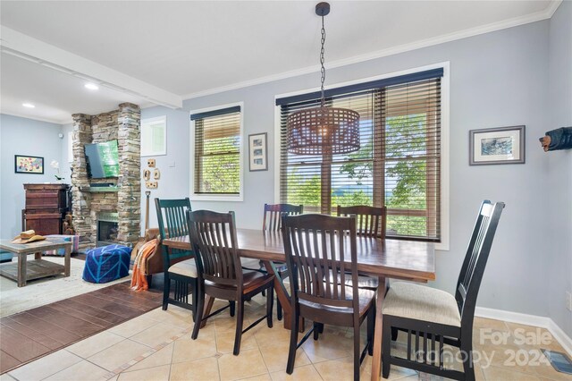 dining space with a wealth of natural light, light tile patterned floors, a fireplace, and ornamental molding