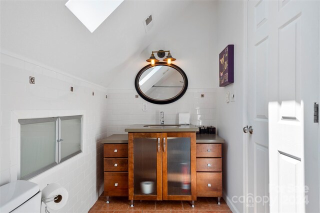 bathroom with toilet, vanity, a skylight, and tile patterned floors