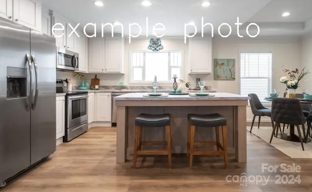 kitchen featuring a breakfast bar, white cabinetry, appliances with stainless steel finishes, and a kitchen island