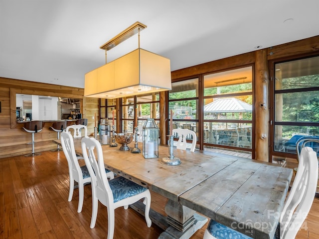 dining space with wood walls and wood-type flooring