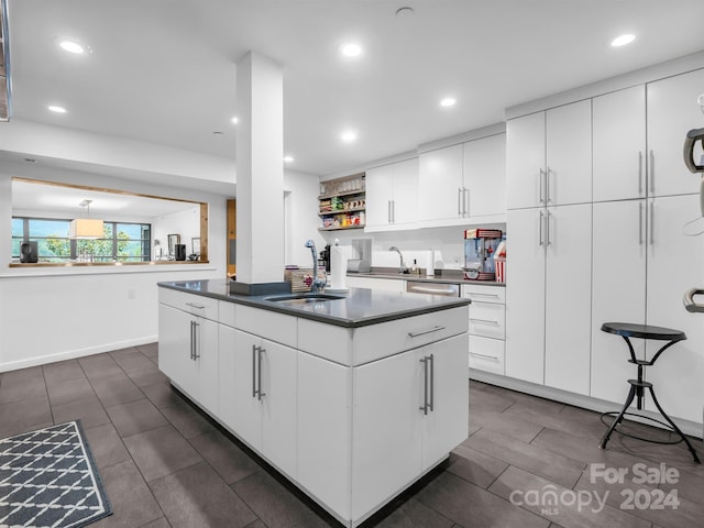 kitchen featuring white cabinetry, sink, a kitchen island, and stainless steel dishwasher