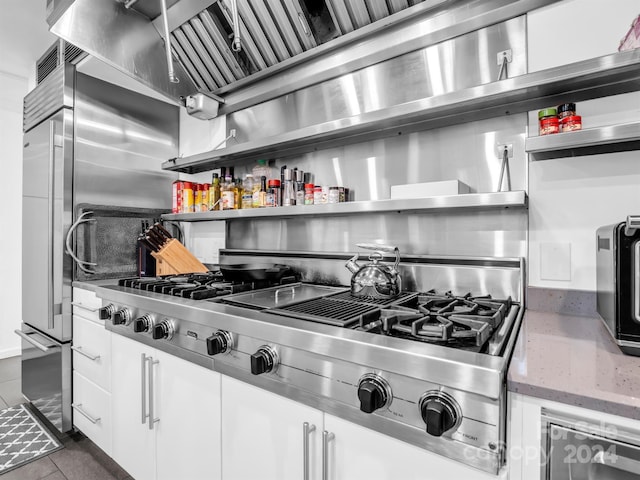 kitchen featuring white cabinets, stainless steel gas stovetop, and dark tile patterned floors