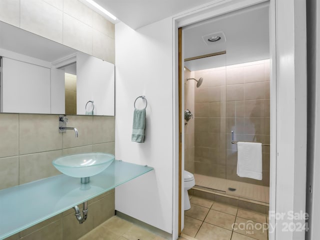 bathroom with backsplash, tile walls, tile patterned flooring, toilet, and a shower with shower door