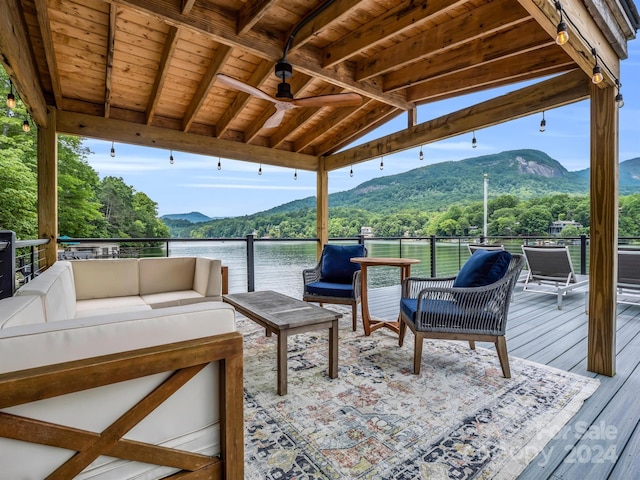 deck featuring an outdoor living space, a water and mountain view, and ceiling fan