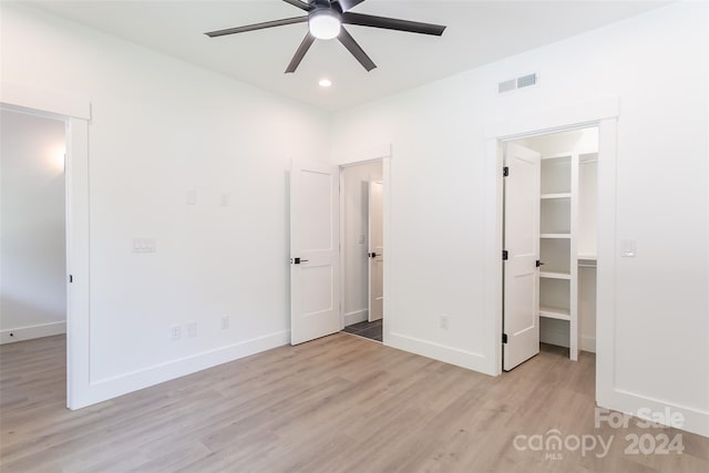 unfurnished bedroom with baseboards, visible vents, a spacious closet, light wood-style floors, and a closet