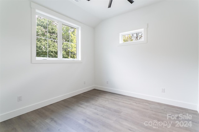 empty room with lofted ceiling, ceiling fan, light wood-style flooring, and baseboards