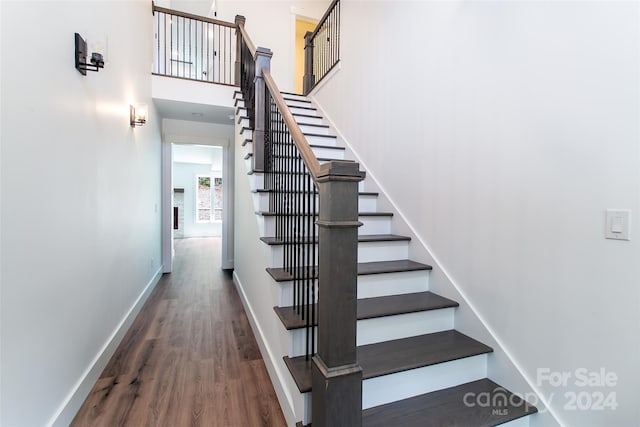 stairs with a towering ceiling, baseboards, and wood finished floors