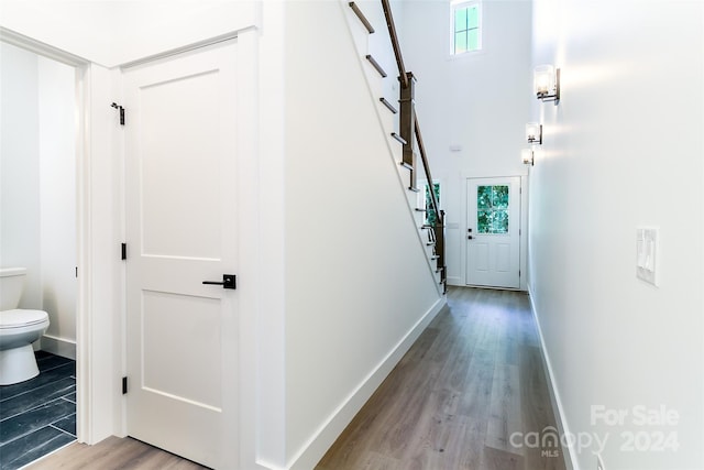 doorway to outside featuring a high ceiling, light wood-style floors, stairs, and baseboards