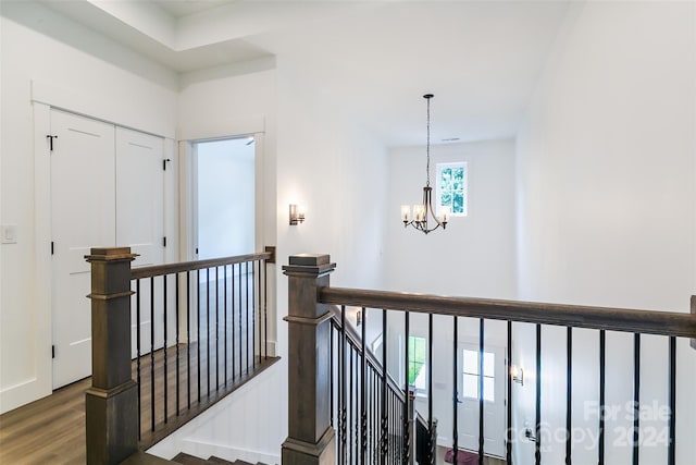 corridor with dark wood finished floors, an upstairs landing, and a notable chandelier