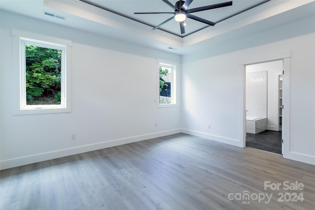 unfurnished bedroom with a raised ceiling, ceiling fan, connected bathroom, and wood-type flooring