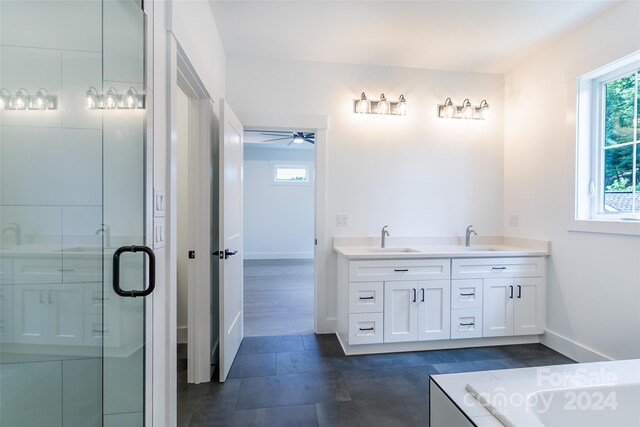 bathroom featuring plenty of natural light, a sink, a bath, and double vanity