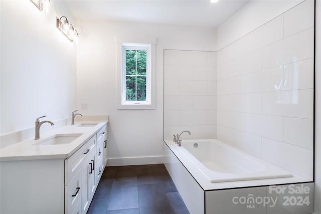 full bathroom featuring double vanity, a sink, a bath, and baseboards