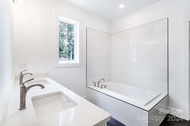 full bathroom featuring recessed lighting, double vanity, a sink, and a bath