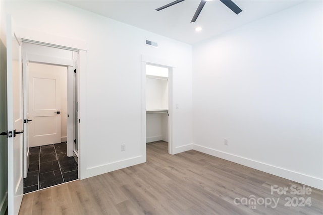 unfurnished bedroom with a walk in closet, dark wood-style flooring, recessed lighting, visible vents, and baseboards