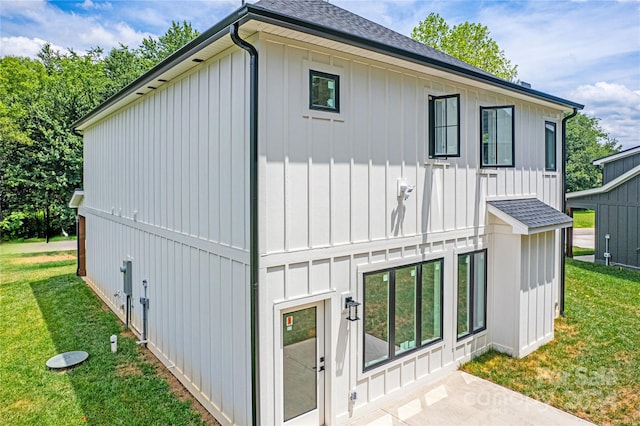 exterior space with a shingled roof, board and batten siding, and a yard