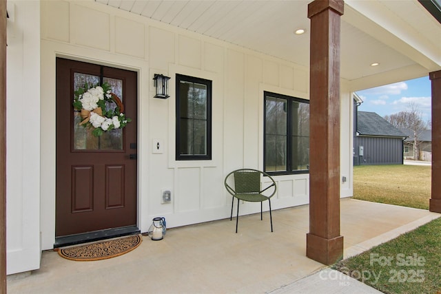 doorway to property featuring a yard, a patio, and board and batten siding