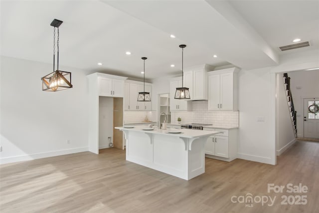 kitchen featuring visible vents, decorative backsplash, light countertops, white cabinets, and light wood-type flooring