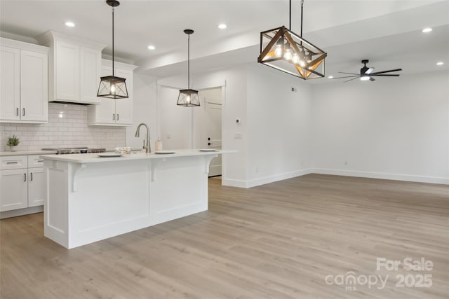 kitchen with tasteful backsplash, light wood-style flooring, white cabinets, and light countertops