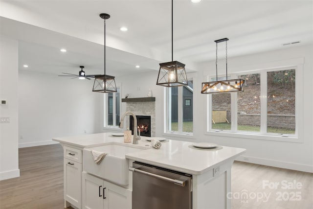 kitchen featuring visible vents, light wood-style flooring, a fireplace, and stainless steel dishwasher