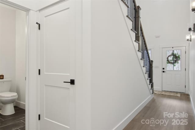 foyer entrance with stairs, wood finished floors, and baseboards