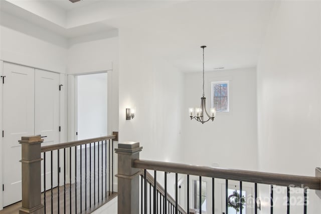 corridor featuring an upstairs landing and a chandelier