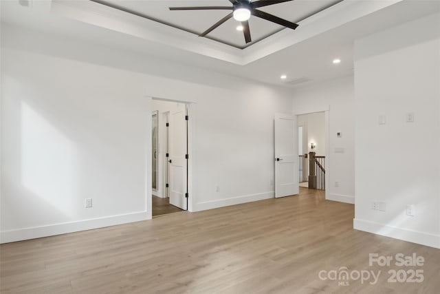 empty room with a ceiling fan, baseboards, recessed lighting, a raised ceiling, and light wood-type flooring