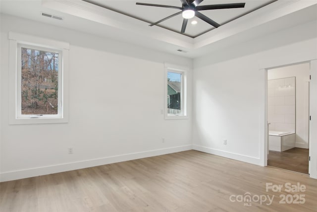 unfurnished bedroom featuring visible vents, baseboards, recessed lighting, light wood-style floors, and a raised ceiling