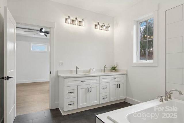 full bath with ceiling fan, double vanity, a tub, and a sink
