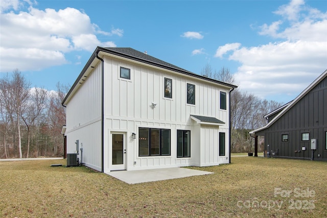 back of house featuring cooling unit, roof with shingles, a lawn, a patio area, and board and batten siding